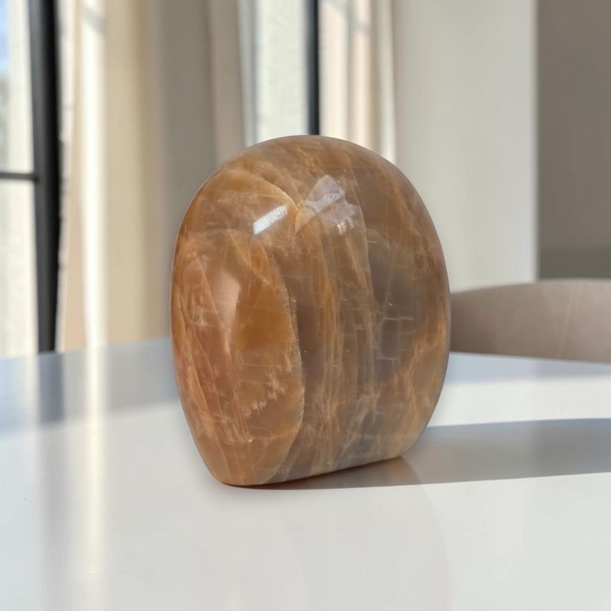 Polished peach-brown freeform crystal stone, rounded base, visible veining
