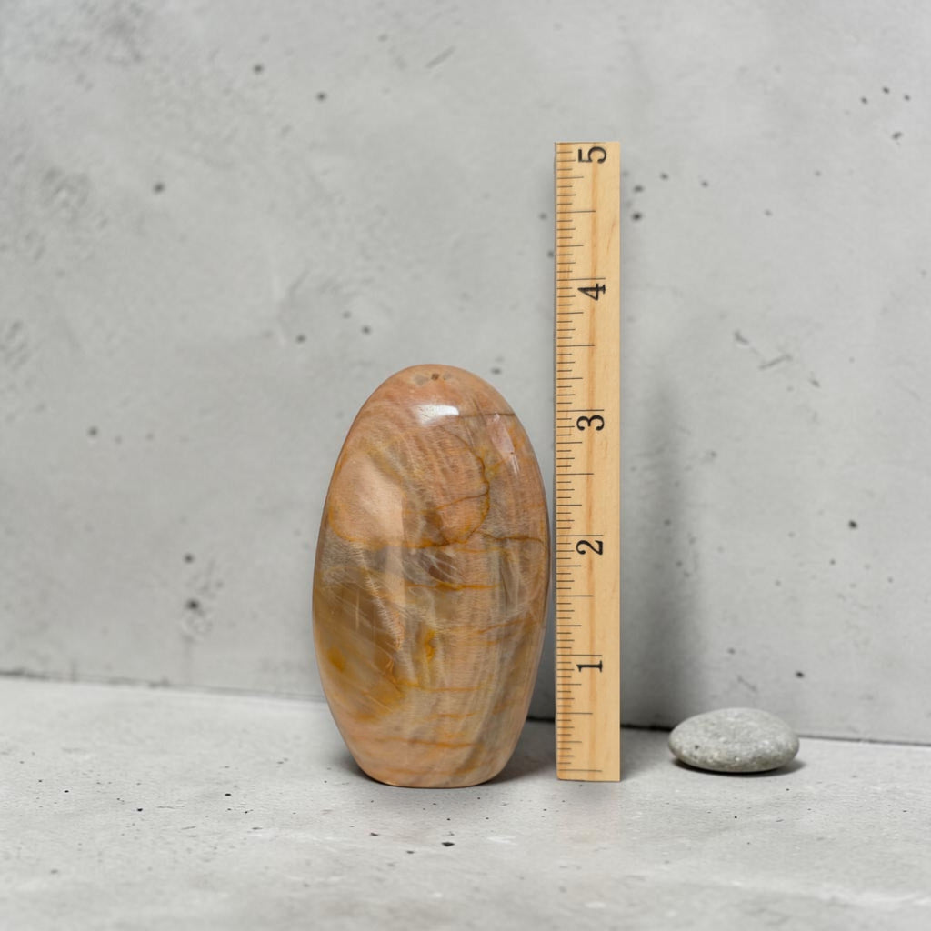 Polished peach moonstone freeform crystal beside ruler, about 2.5 in tall.