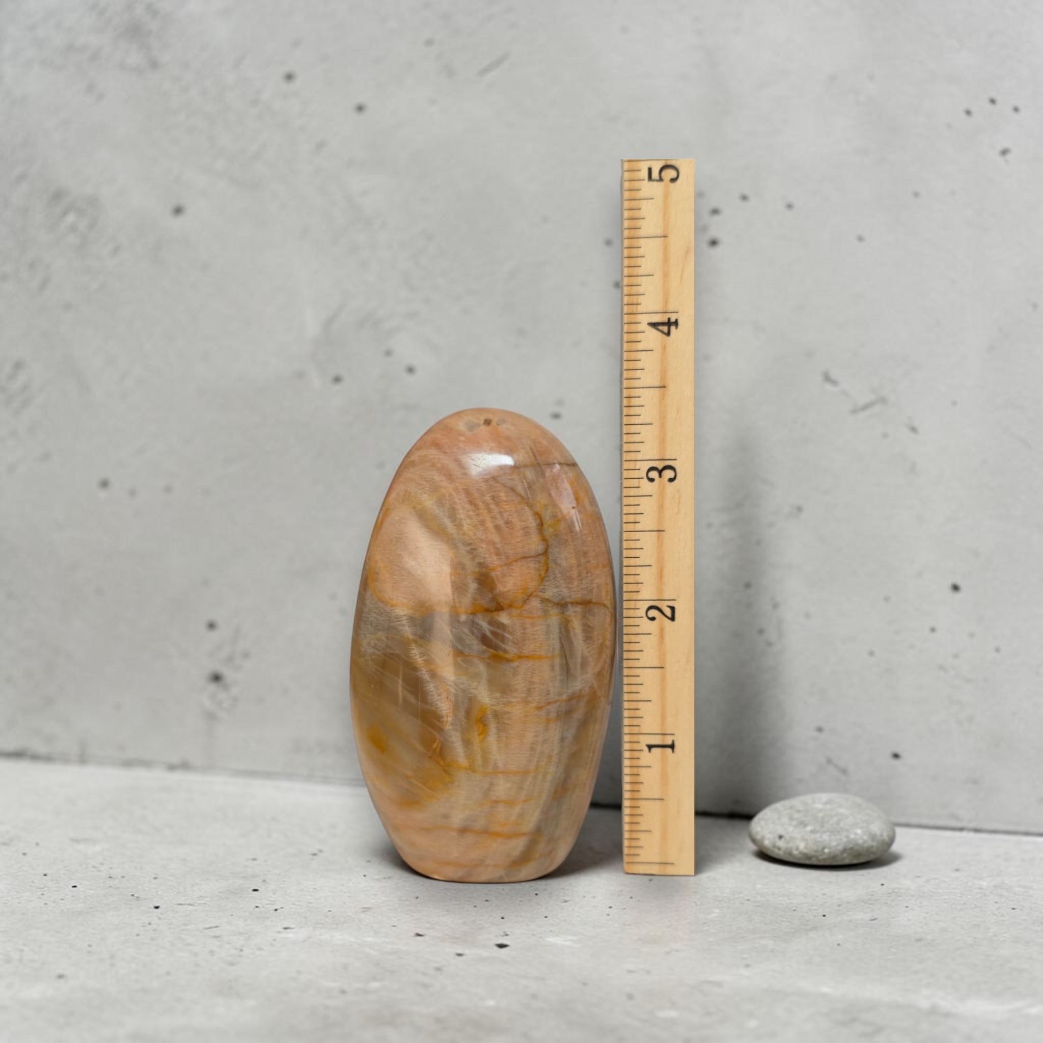 Polished peach moonstone freeform crystal beside ruler, about 2.5 in tall.