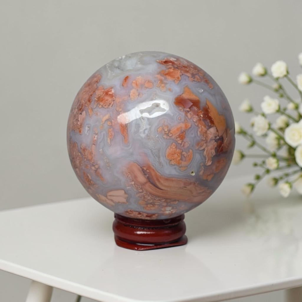 Agate sphere on stand, cool blue-gray with scattered orange patches