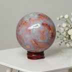 Agate sphere on stand, cool blue-gray with scattered orange patches