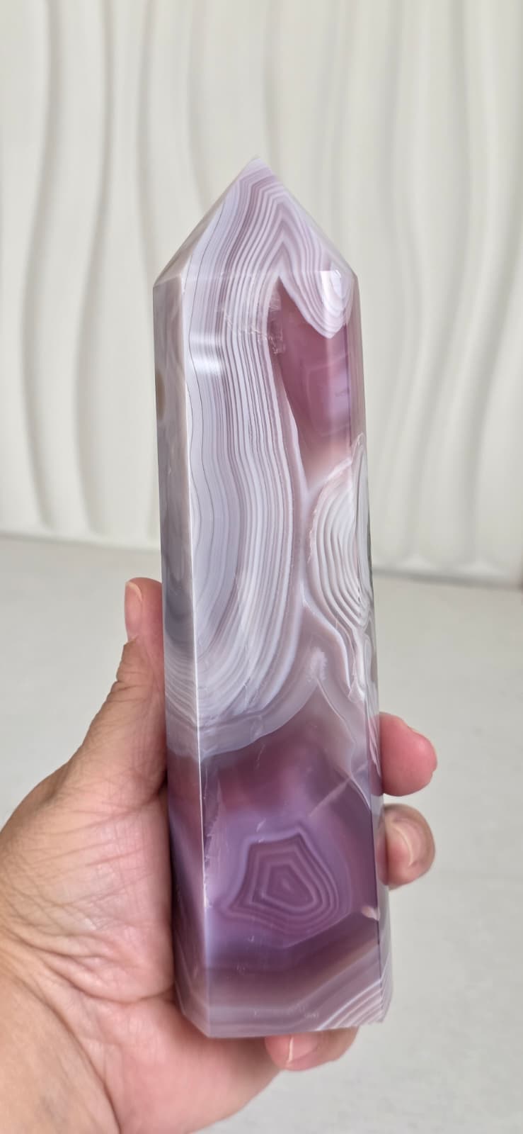 Handheld pink and purple agate crystal tower with banded layers and druzy cavity