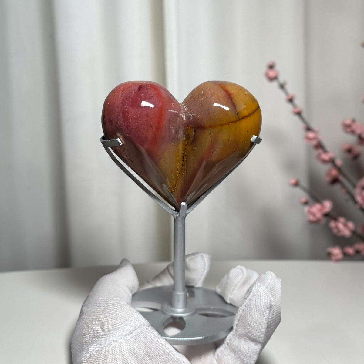 Pink and mustard yellow mookaite jasper heart with dark contrasting lines on a silver tone stand