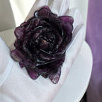 Purple fluorite rose carving held in gloved hand, closeup of deep violet color