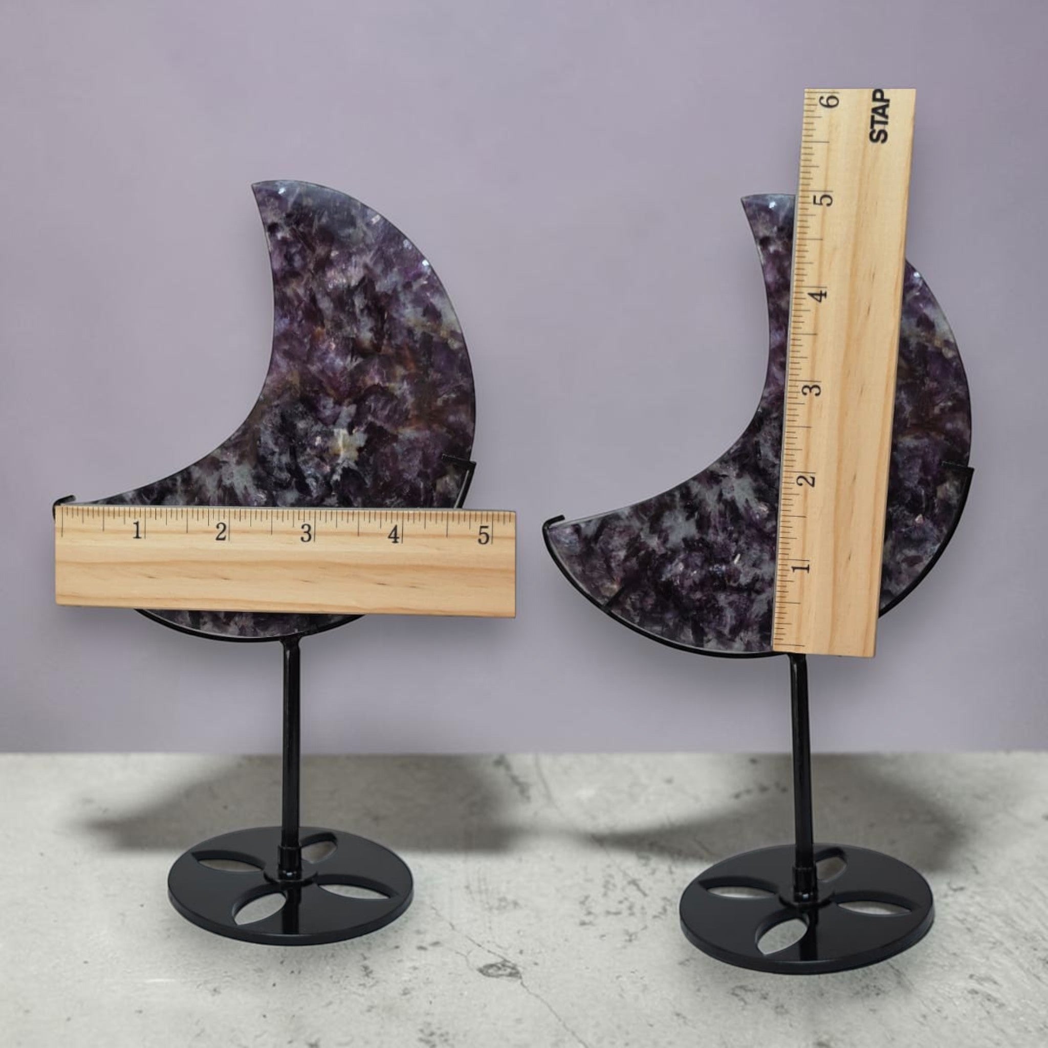 Purple speckled crescent moon crystal decor on black metal stand with measuring ruler