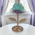 Rainbow fluorite rose on gold stand displayed by window with natural light