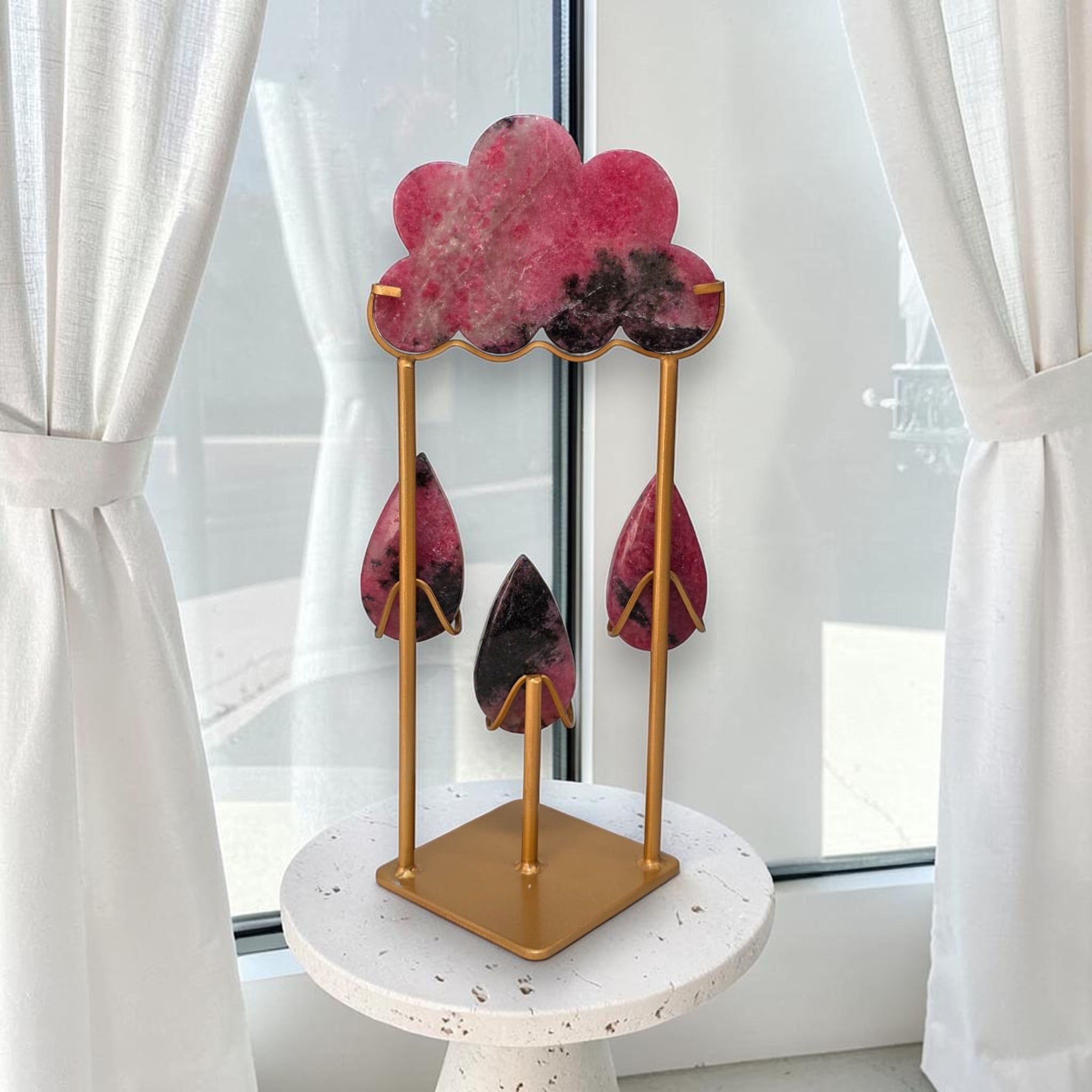 Rhodonite rain cloud crystal sculpture on gold stand with pink cloud and teardrops, on round base