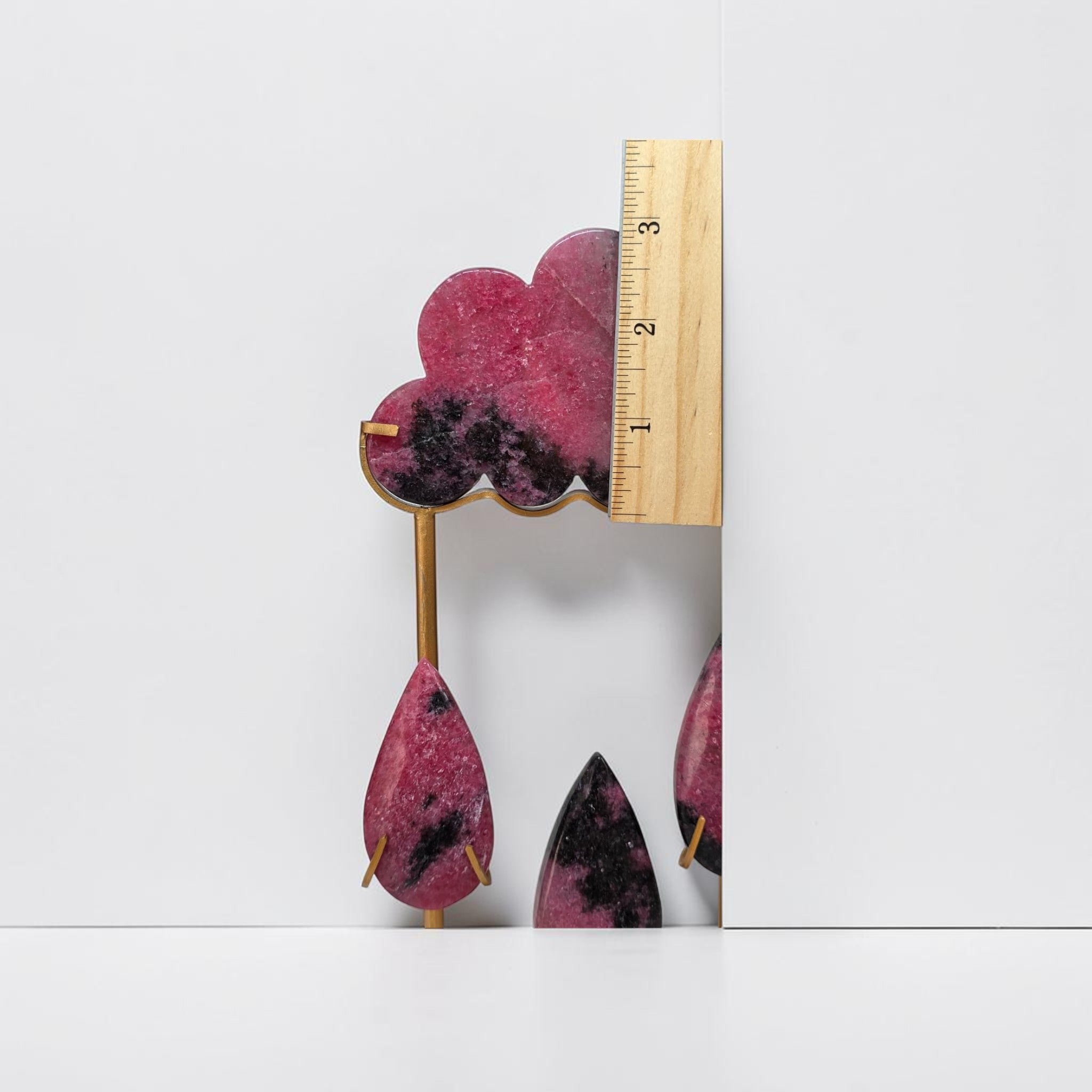 Rhodonite rain cloud crystal sculpture, side view with ruler beside pink cloud and hanging teardrops
