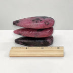 Rhodonite polished stone stack with ruler for scale; pink pieces with dark streaks