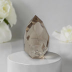 Smoky quartz faceted freeform on white round base, large cut crystal
