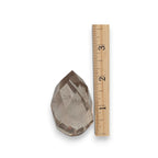 Smoky quartz faceted freeform next to measuring ruler
