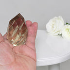 Smoky quartz faceted freeform, close-up held in open palm