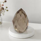 Smoky quartz faceted freeform on white round base, large faceted teardrop crystal