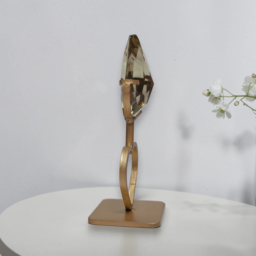 Side view of faceted smoky quartz crystal on gold tone heart stand