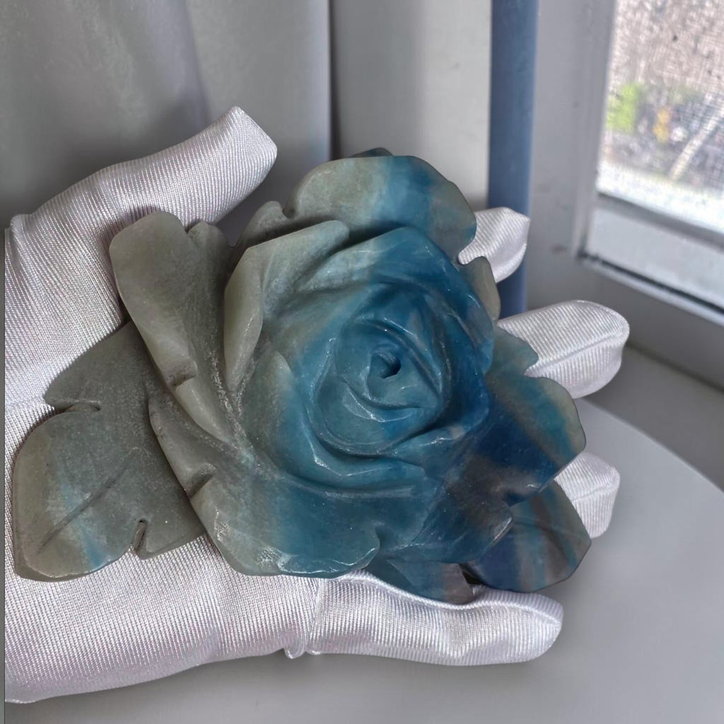 Natural Trolleite rose carving held in gloved hand showing size and blue-grey color detail
