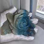 Natural Trolleite rose carving held in gloved hand showing size and blue-grey color detail