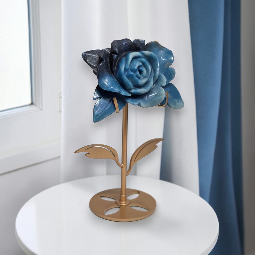 Natural Trolleite rose carving on gold stand on marble surface, side view