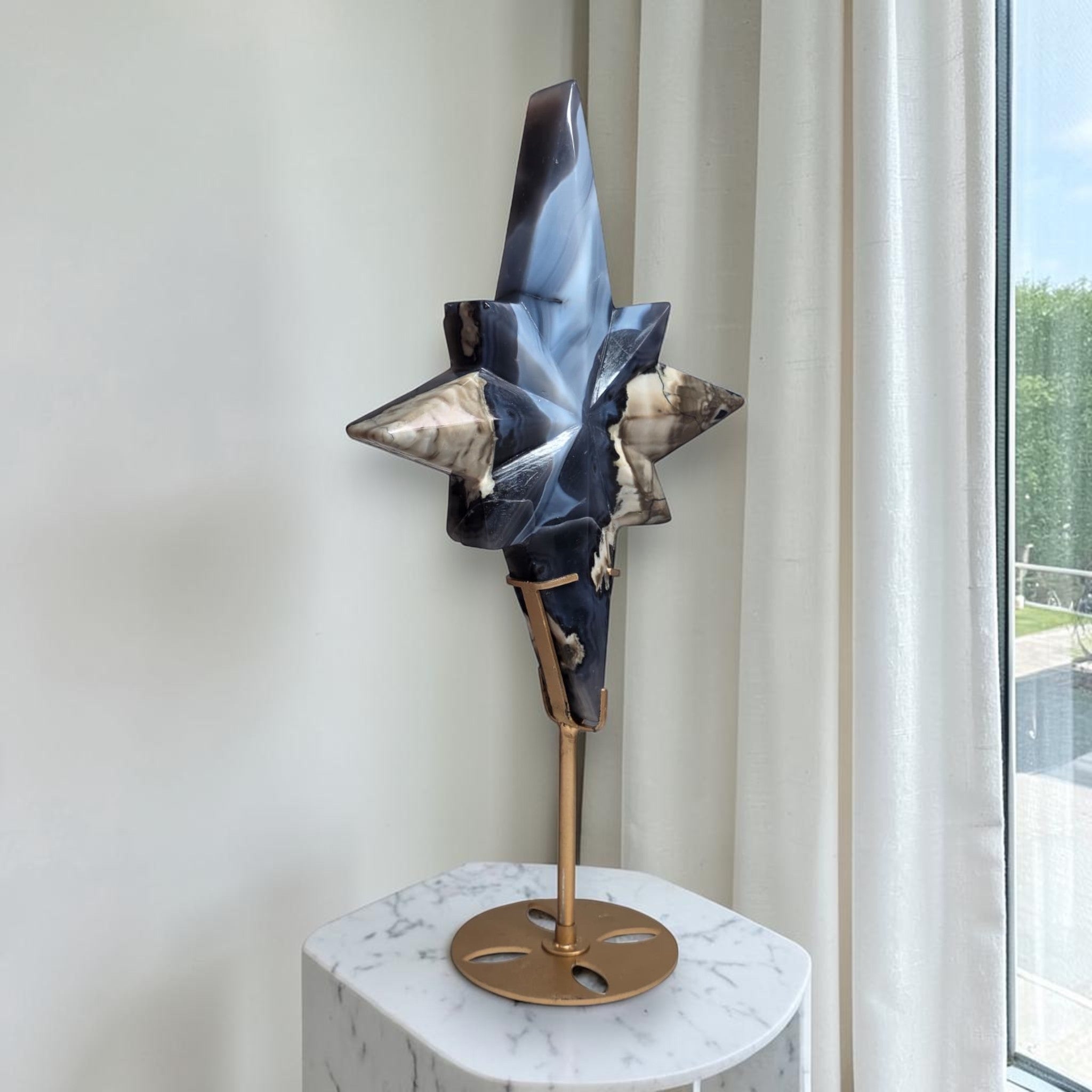 North star crystal sculpture with blue and gray stone-like facets on a round bronze base.