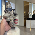 Hand holding star-shaped agate crystal carving, gray and white with dark blue sections