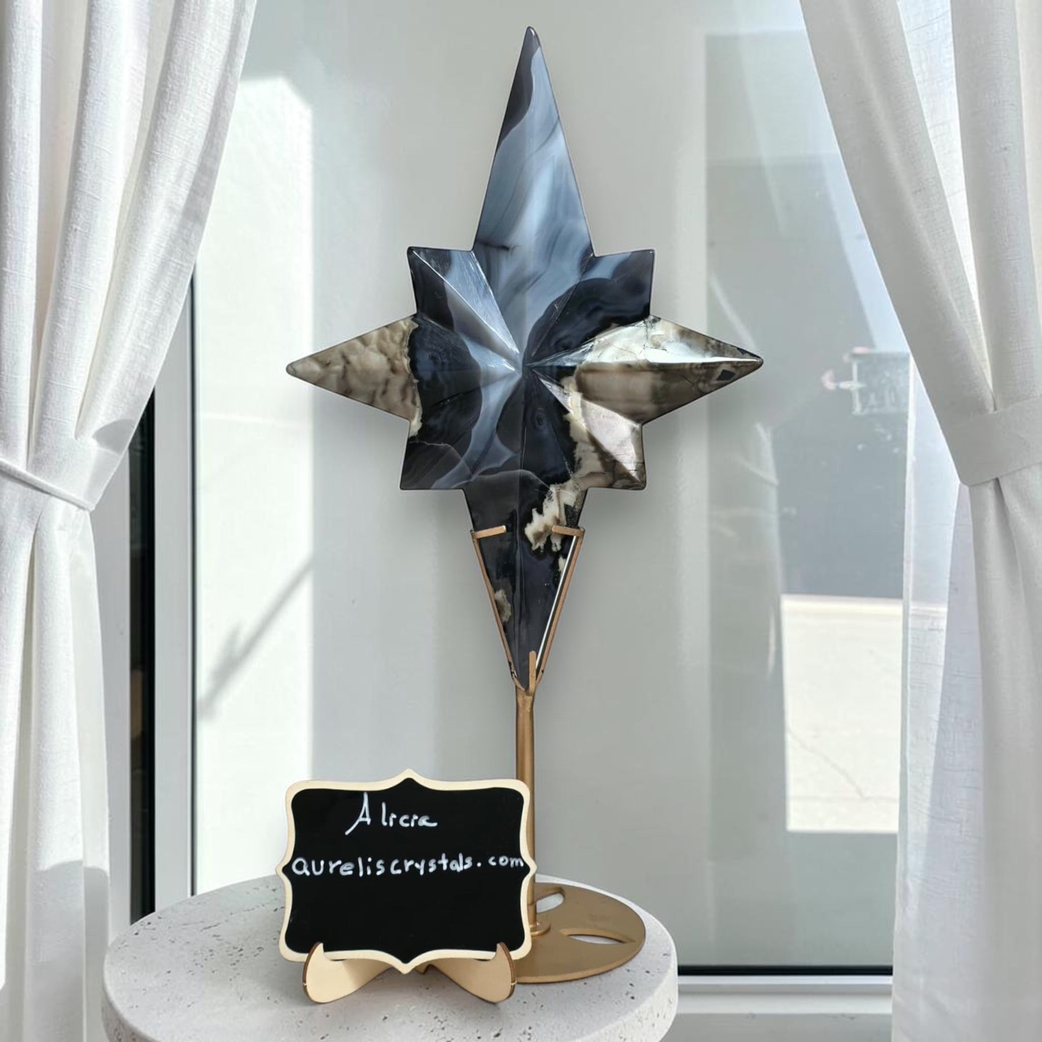 Blue, black, and smoky star crystal sculpture on a gold stand atop a marble-style base.