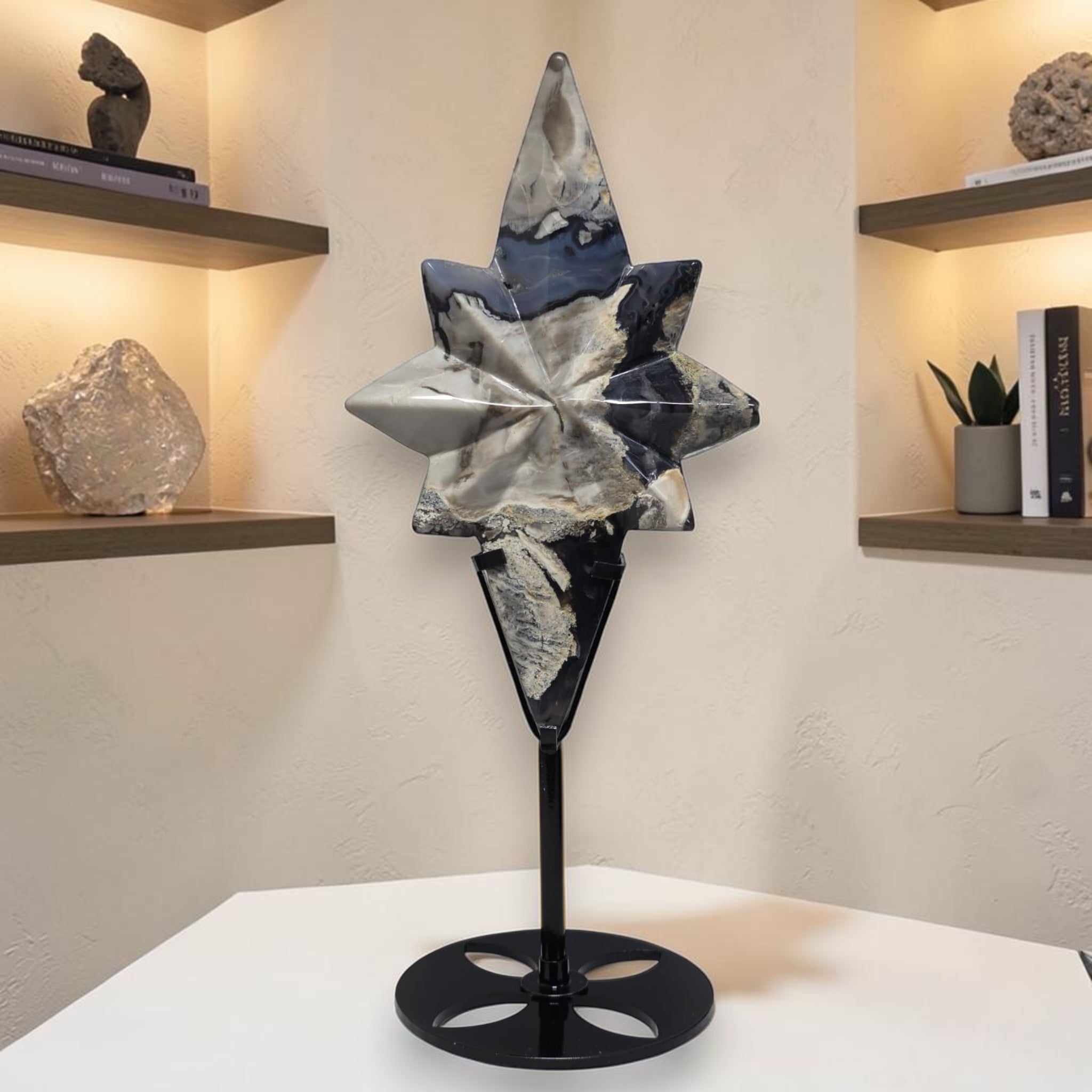 Star-shaped agate crystal carving on black pedestal stand, gray and deep blue