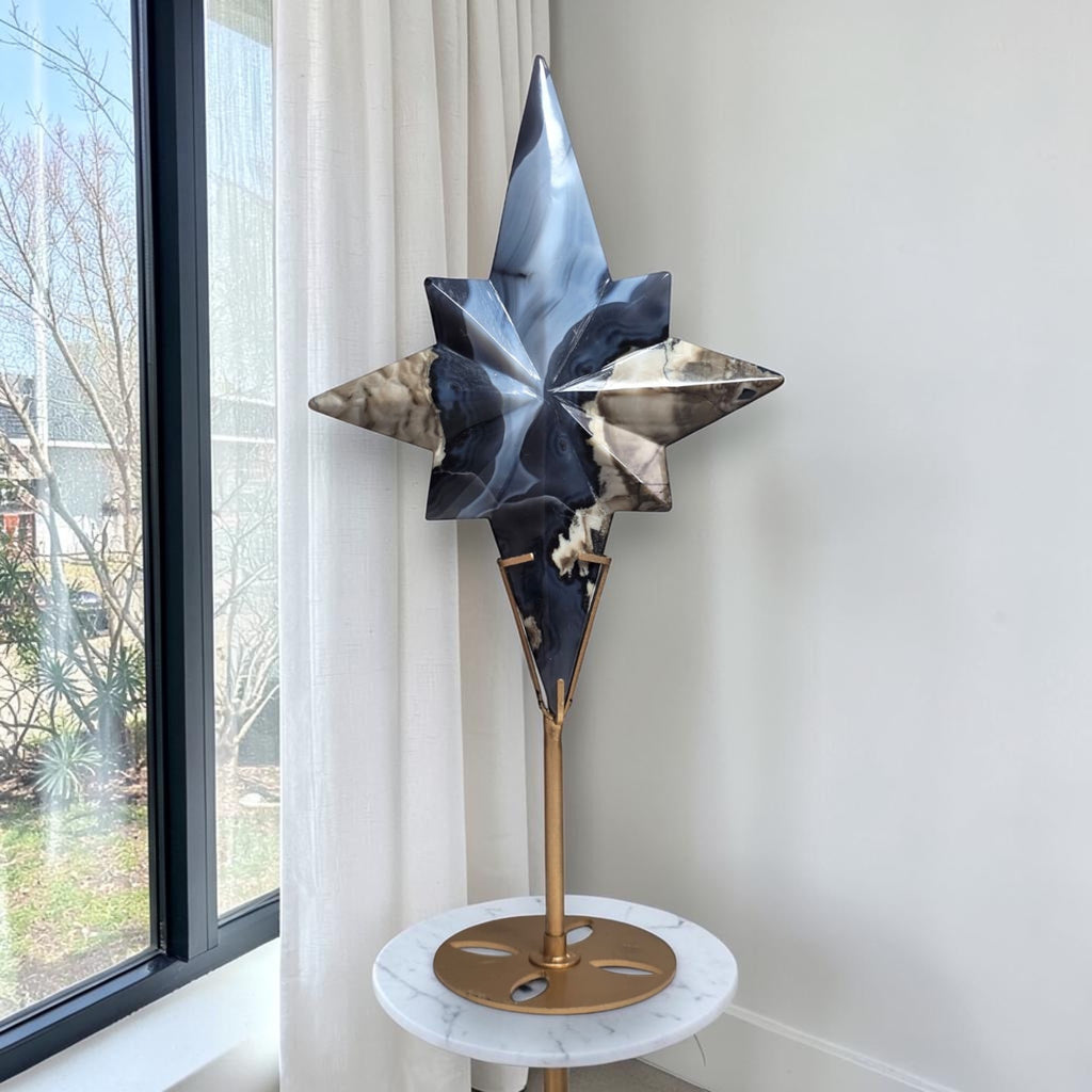 Star-shaped crystal sculpture with blue and dark facets standing on a round marble-style base.