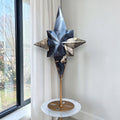 Star-shaped crystal sculpture with blue and dark facets standing on a round marble-style base.